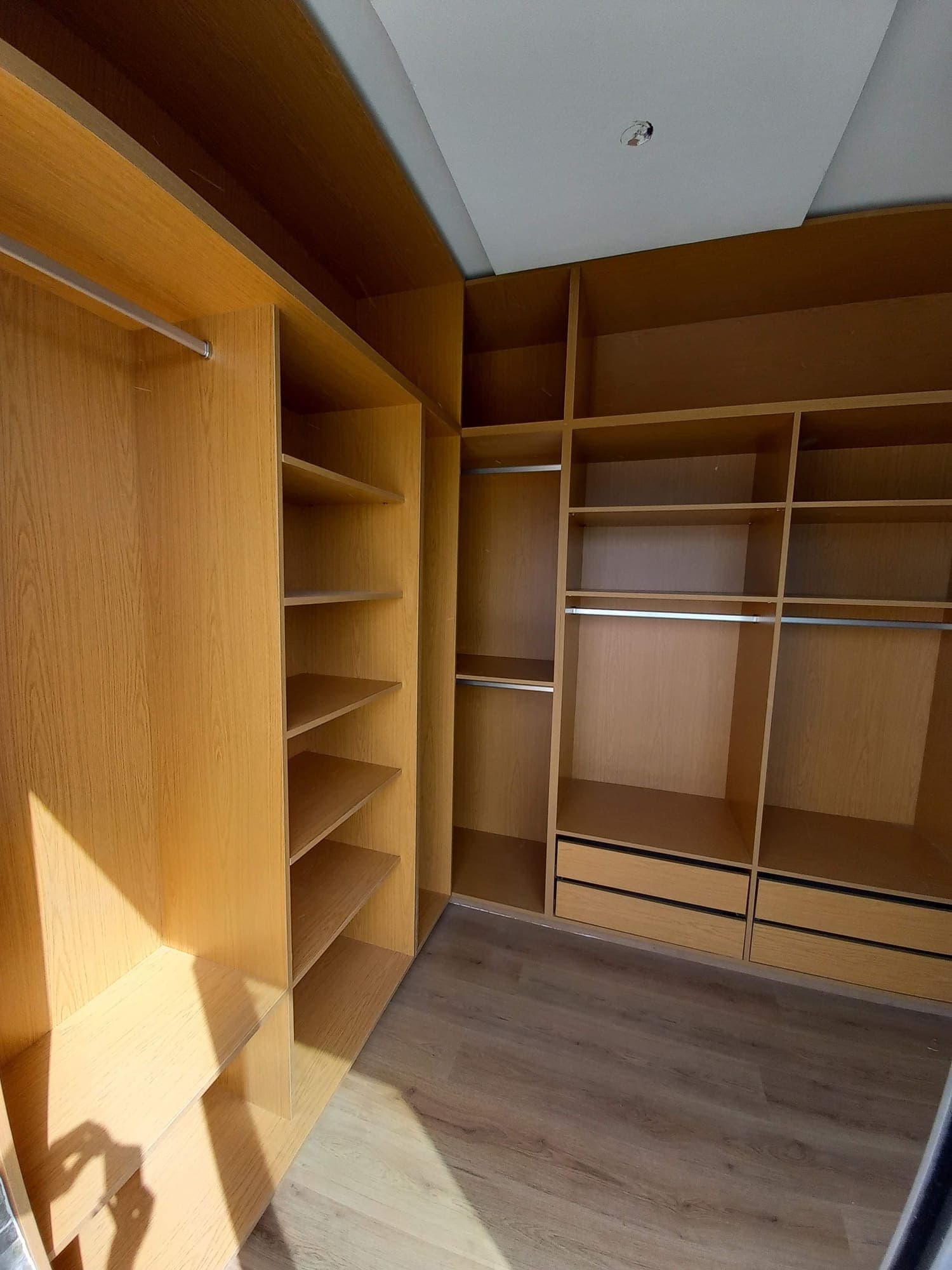 Dressing en bois clair avec penderies, étagères et tiroirs