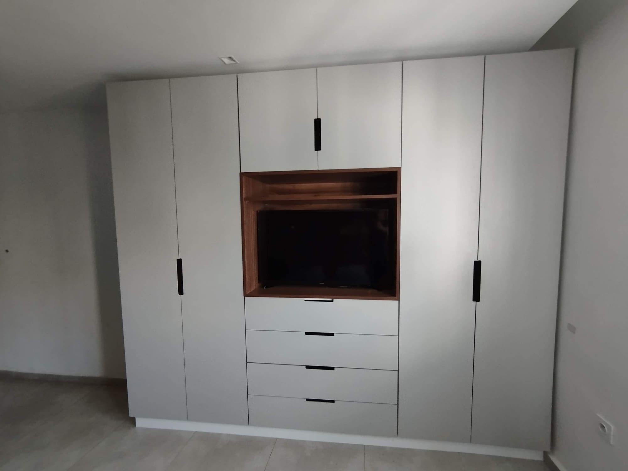 Placard blanc à portes sans poignée avec niche TV en bois et tiroirs