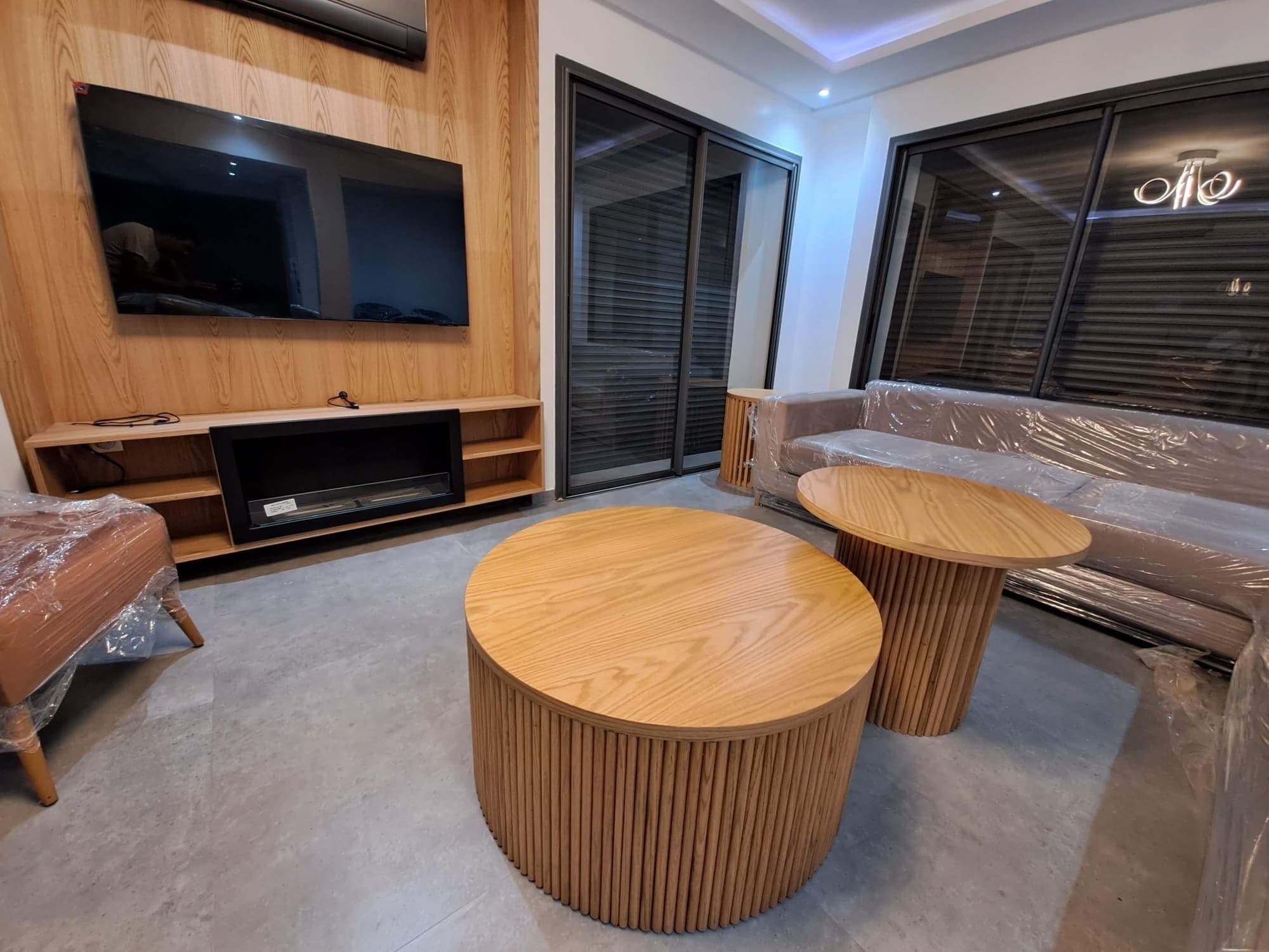 Séjour avec meuble TV en bois, cheminée et tables basses cylindriques à lames